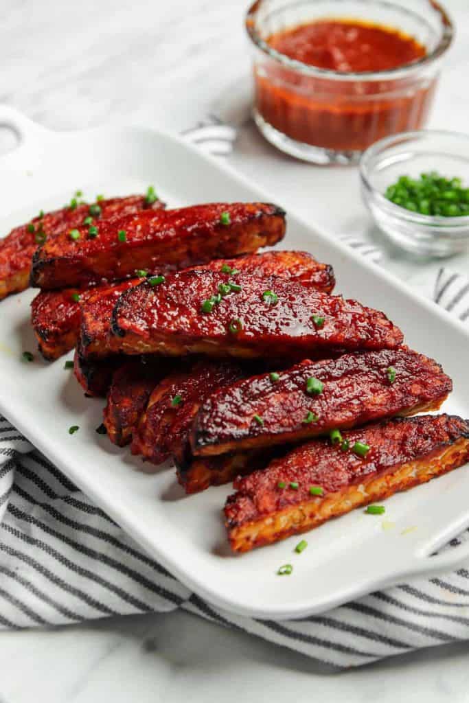 vegan BBQ tempeh served on a white plate garnished with chives