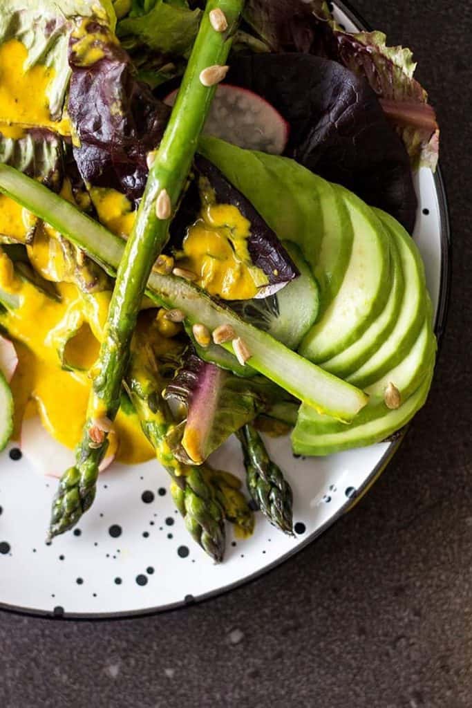 Salad with asparagus, lettuce, avocado, and creamy turmeric dressing. 