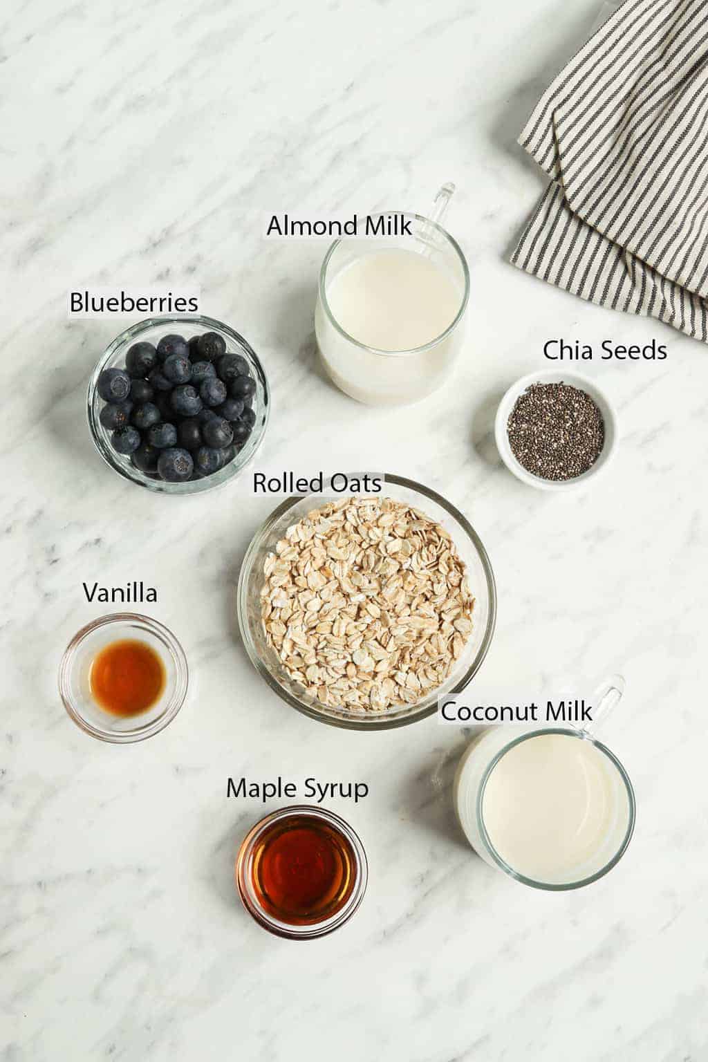 Ingredients for overnight oats measured out and placed on a marble countertop. 