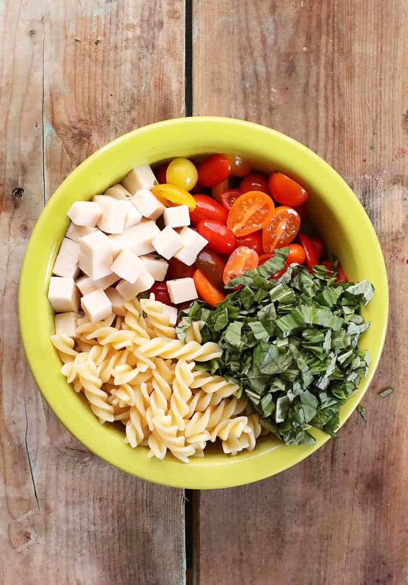 Tomatoes, pasta, basil, and cheese in bowl