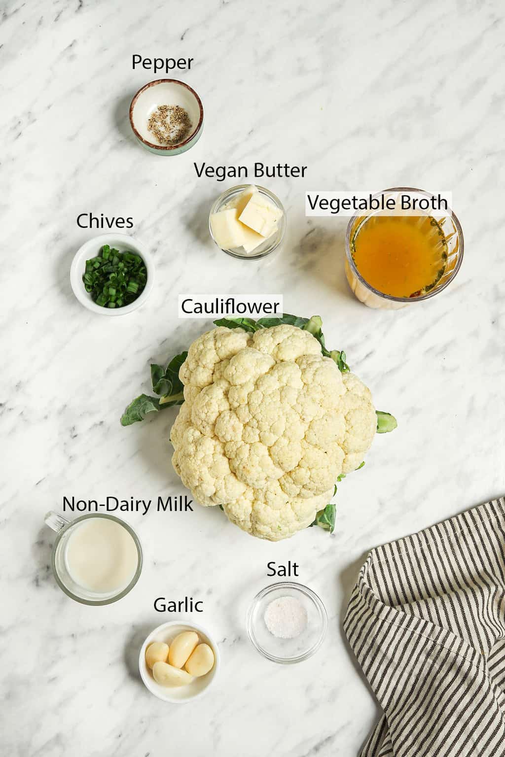 Ingredients for mashed cauliflower measured out and placed on a marble countertop. 