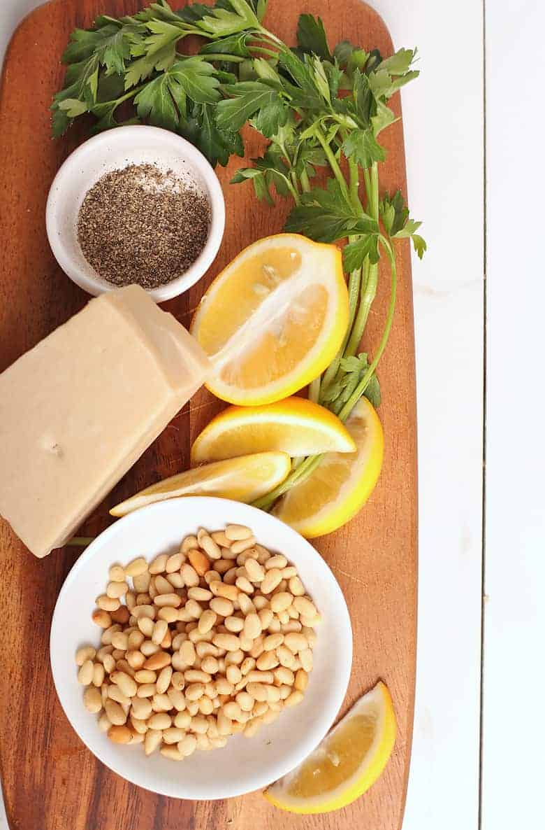 lemon, parsley, pine nuts, and pepper on a wooden board. 