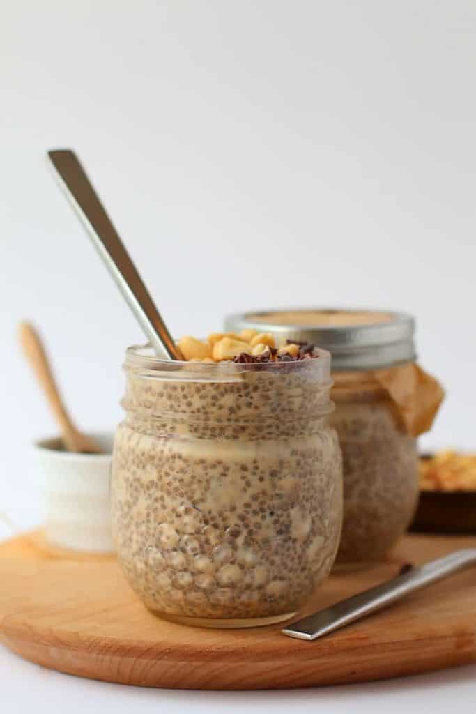 Two jars of chia pudding on a wooden platter