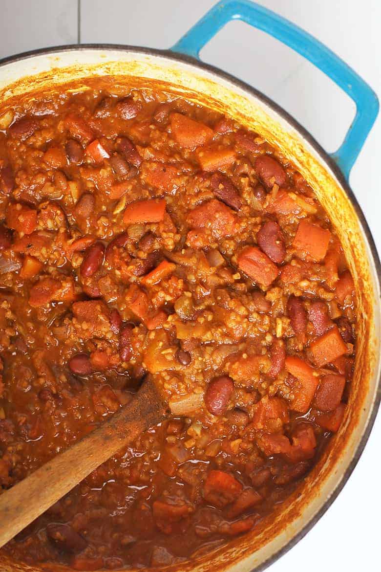 vegan chili in a large soup pot with a wooden spoon
