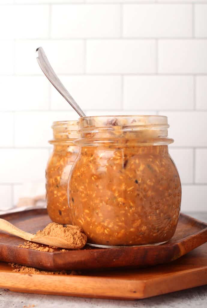 sideways shot of a mason jar filled with peanut butter chocolate overnight oats with a subway tile background