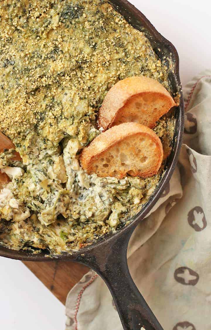 Vegan Spinach Artichoke Dip with Toasted Baguette in a skillet. 
