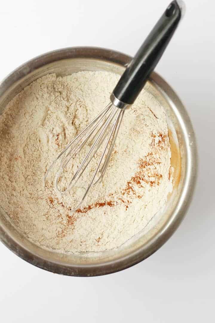 Flour and spices in a bowl with a whisk.