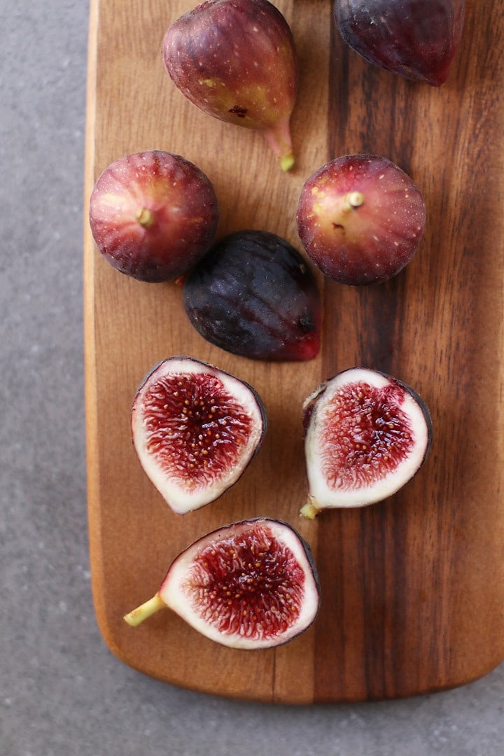 Whole and halved figs on a wooden platter