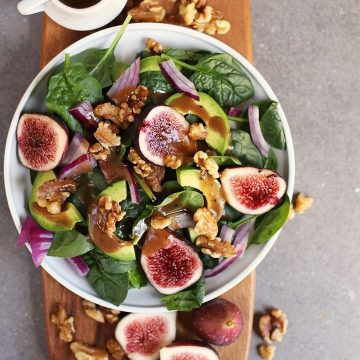 Finished salad on a wooden platter with fresh figs