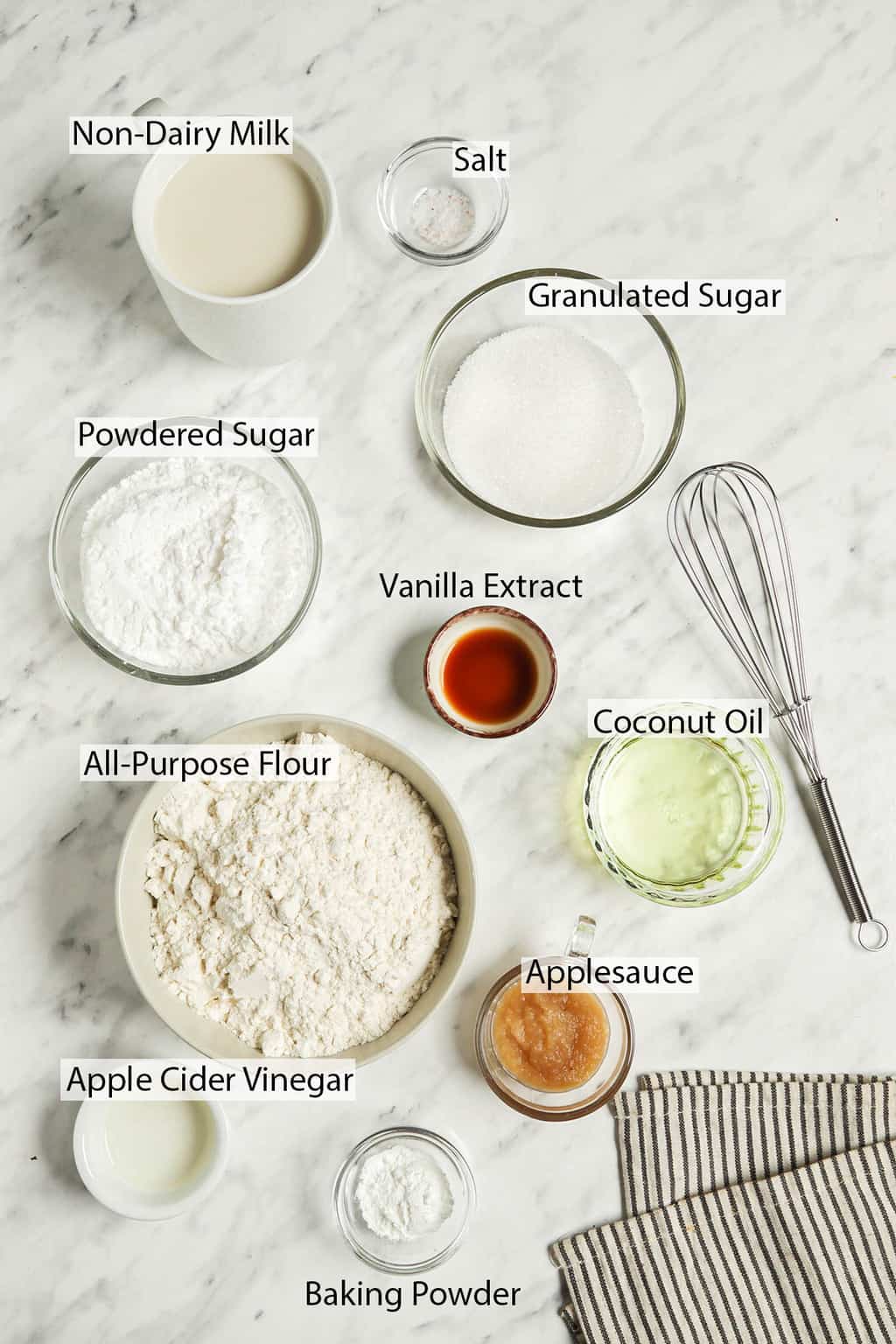 Ingredients for glazed doughnuts measured out and placed on a marble countertop. 