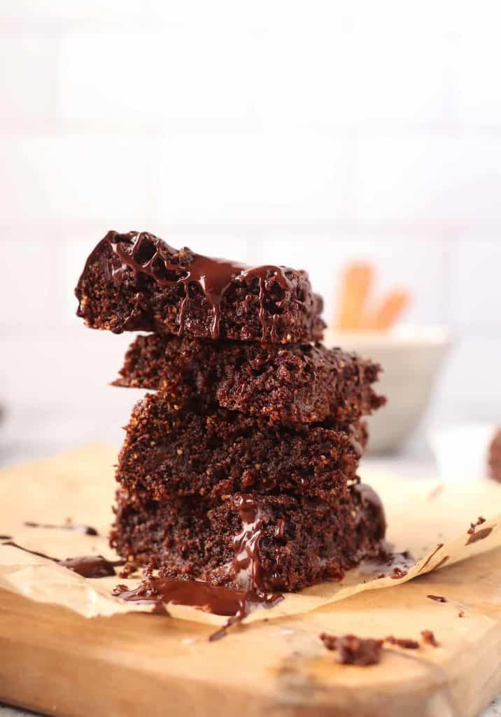 stack of melty gooey vegan gluten free brownies on a piece of parchment paper