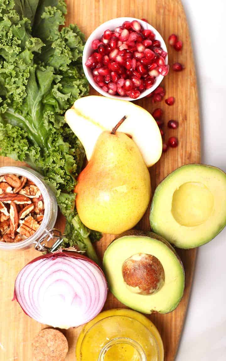 Pears, avocados, onions, and kale on cutting board
