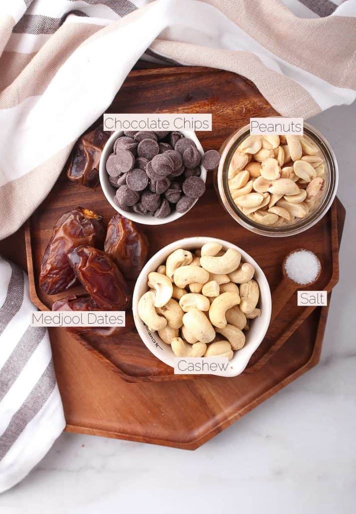 Cashews, peanuts, chocolate chops, and Medjool dates on a wooden platter