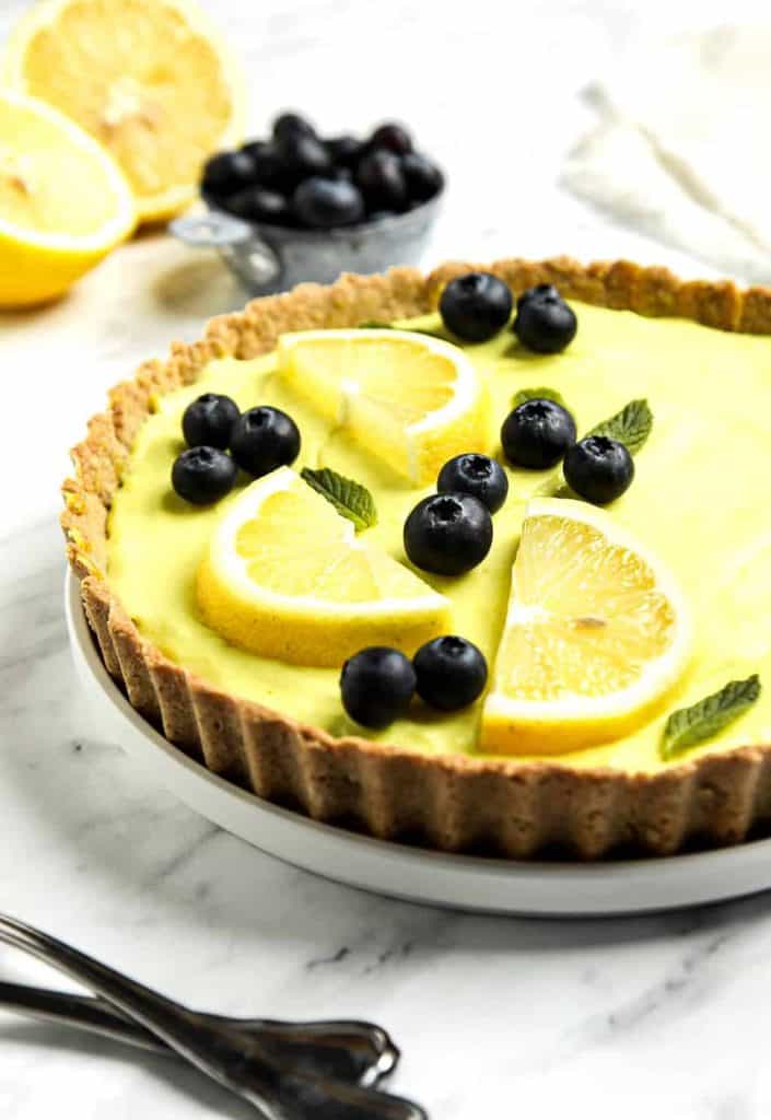 vegan lemon tart topped with lemon slices and blueberries