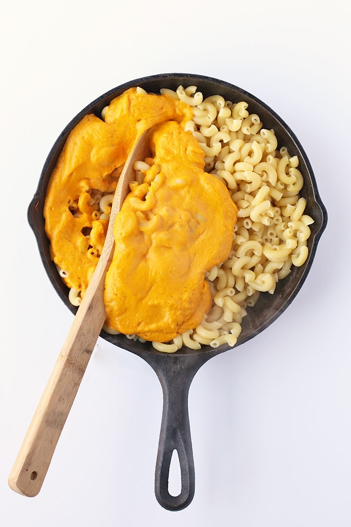 Elbow noodles mixed with cheesy sauce in a cast iron skillet