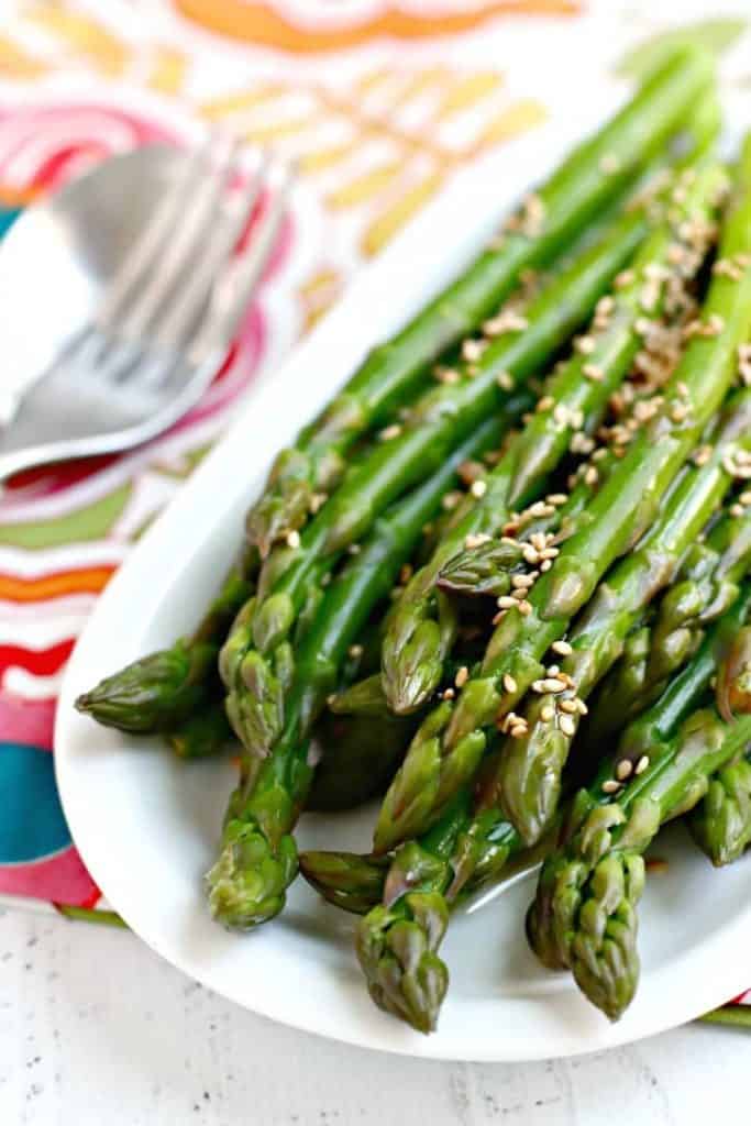Plate of marinated asparagus stalks with sesame seeds. 