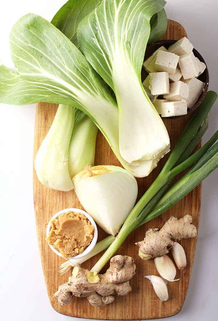 Ginger, garlic, miso paste, and onions on cutting board