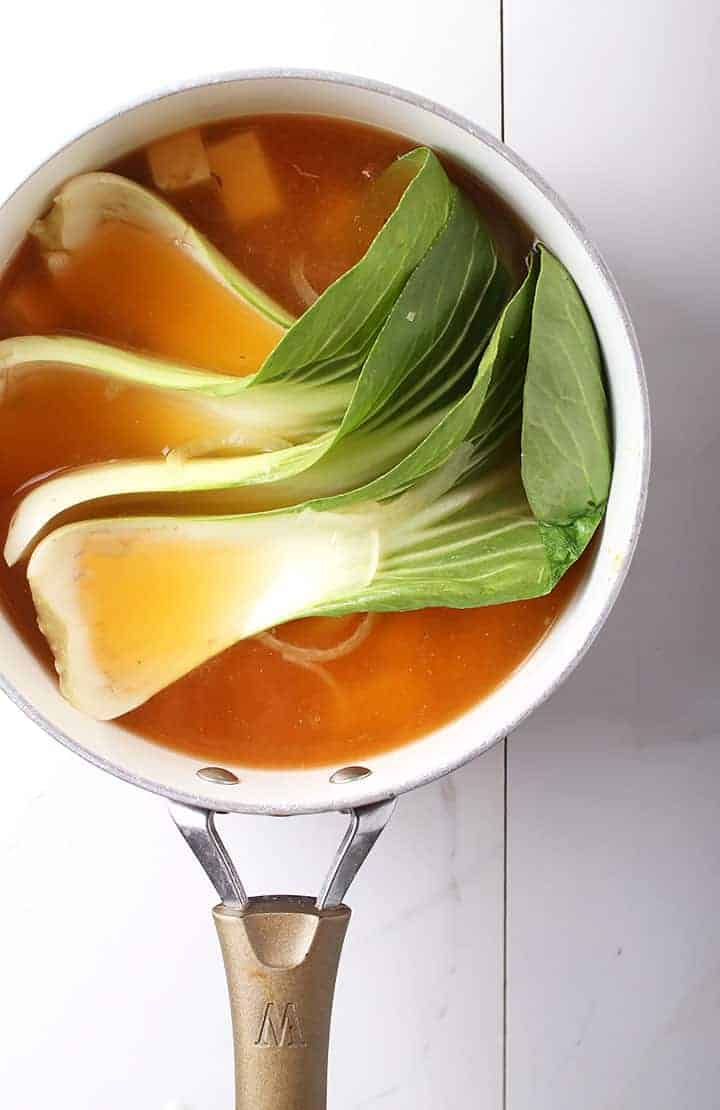 Bok choy in soup pot with broth
