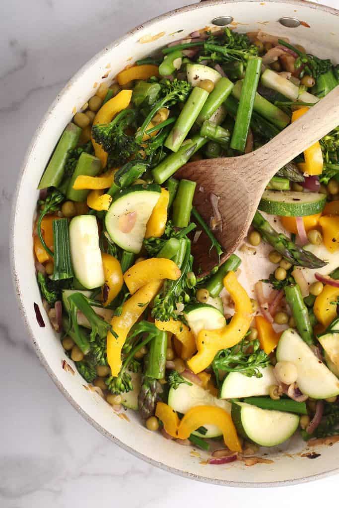 A mixture of spring vegetables in a cast iron skillet
