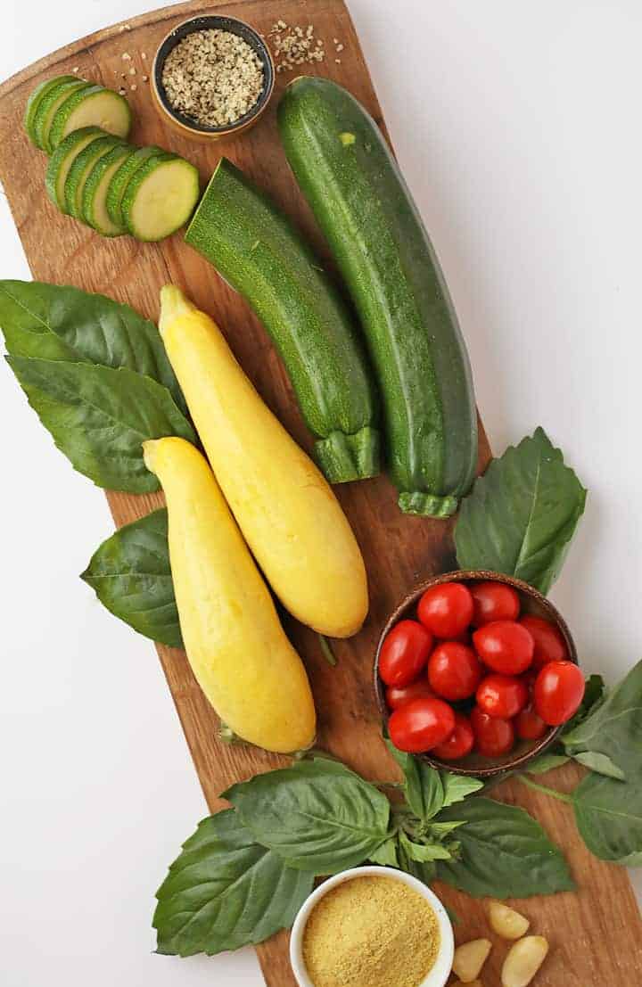 Zucchini, summer squash, and cherry tomatoes on a cutting board