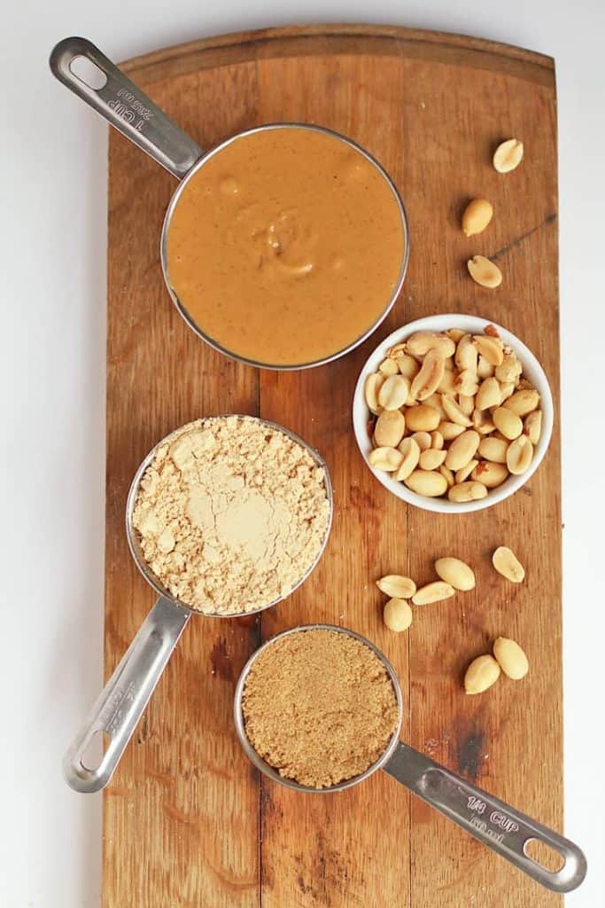 Peanut butter, peanut flour, and peanuts on a wooden board