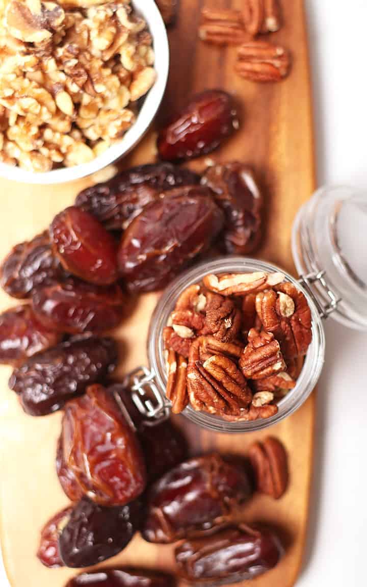 Dates, pecans, and walnuts on wooden platter