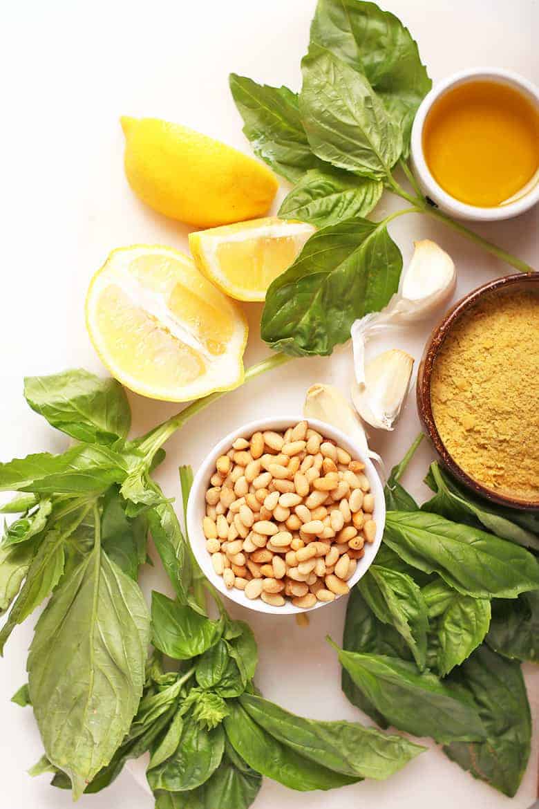 Lemon, basil, and pine nuts on a cutting board