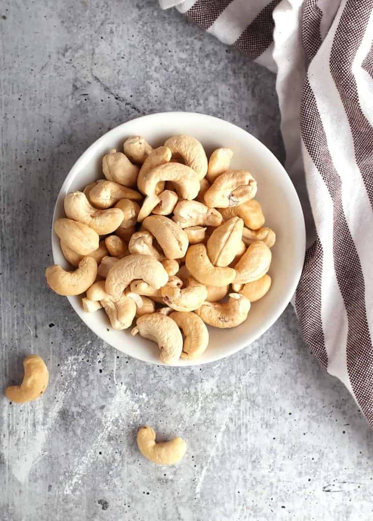 Small white bowl of raw cashews