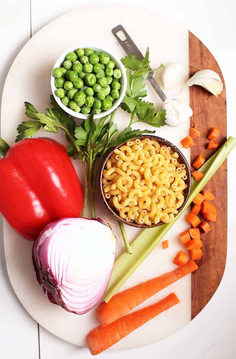 Carrots, onions, bell pepper, and peas on a cutting board