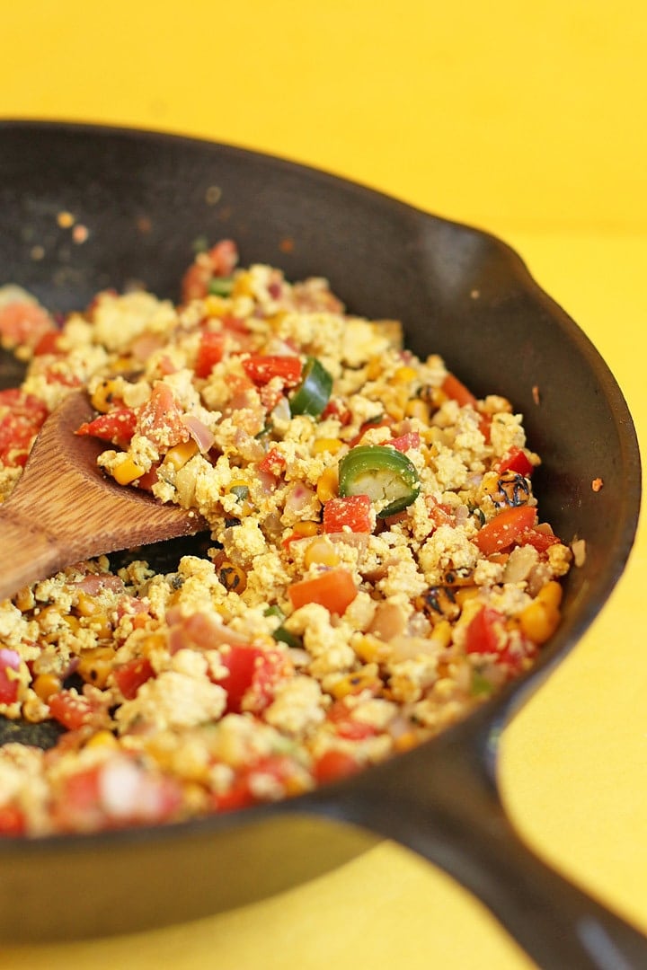 Mexican Tofu Scramble in a cast iron skillet with a wooden spoon