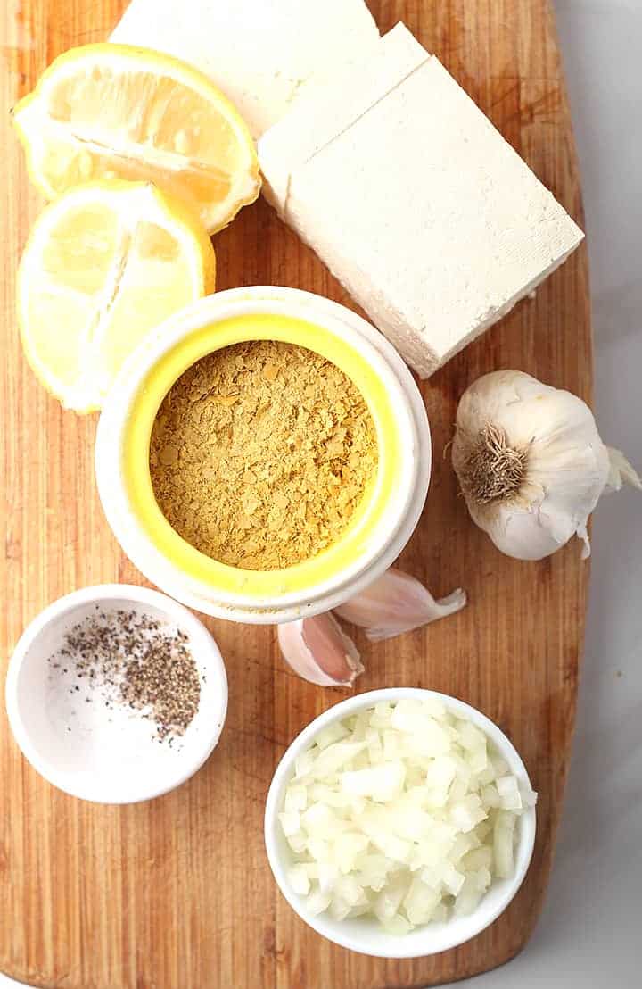 Nutritional yeast, tofu, lemon, and garlic on a cutting board