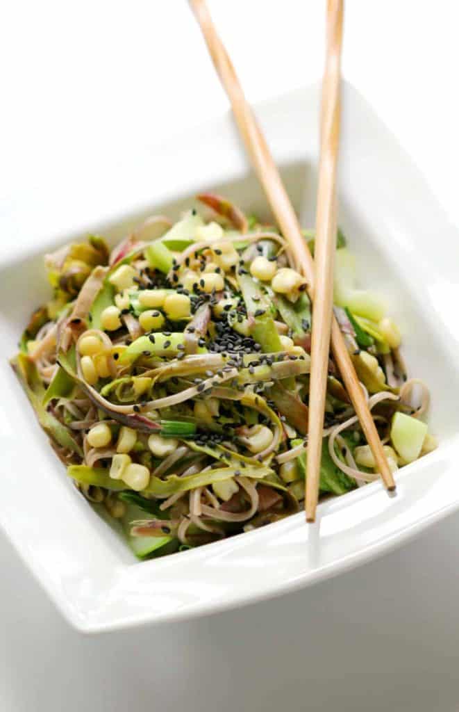 Asparagus and Asian vegetable soba noodles in a white bowl with chopsticks 