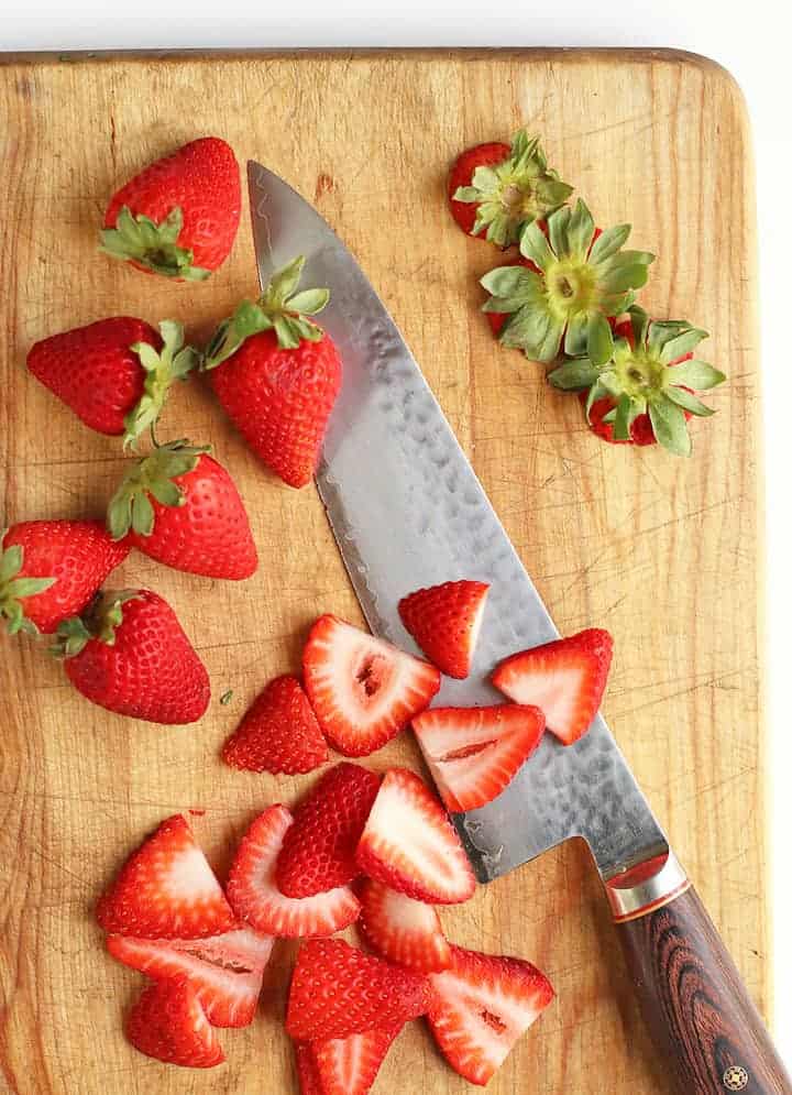 Chopped strawberries on a wooden cutting board