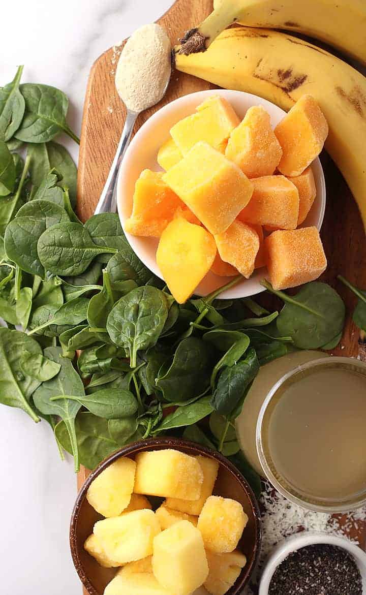 Spinach, mango, banana, and pineapple on wooden platter