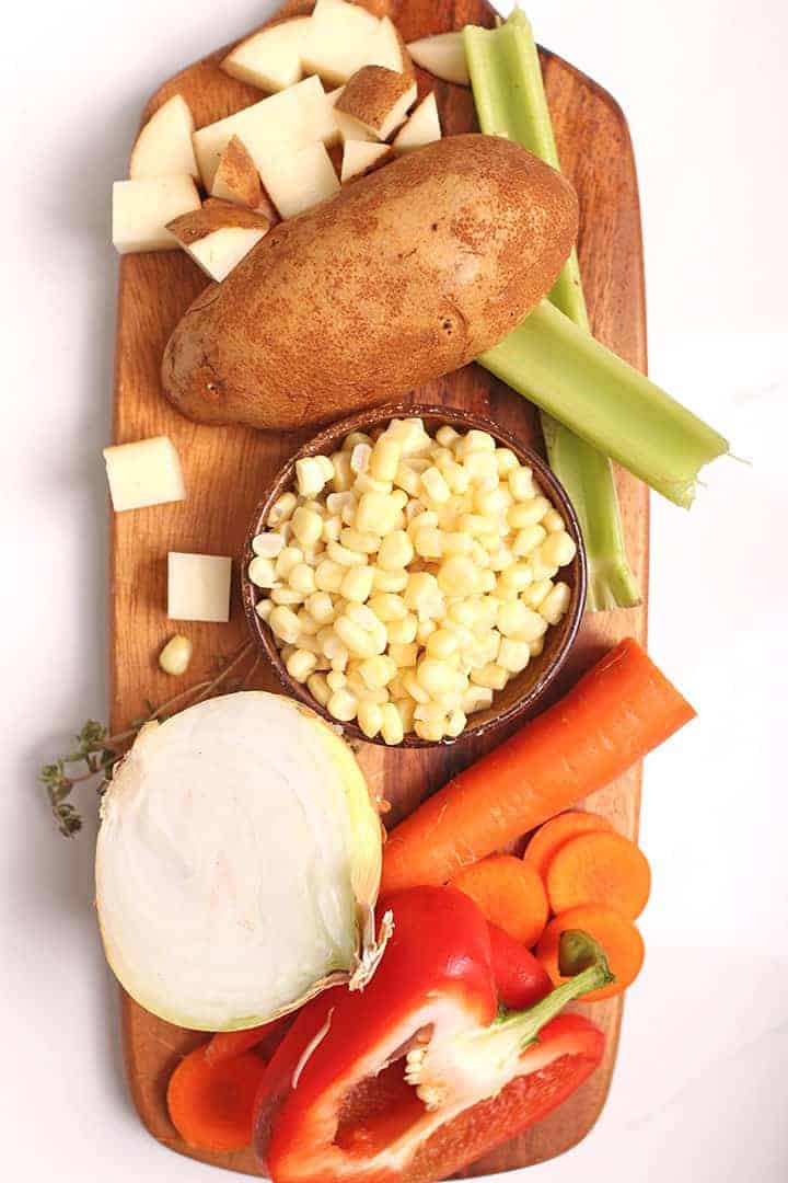 Corn, onions, pepper, and, potato on cutting board