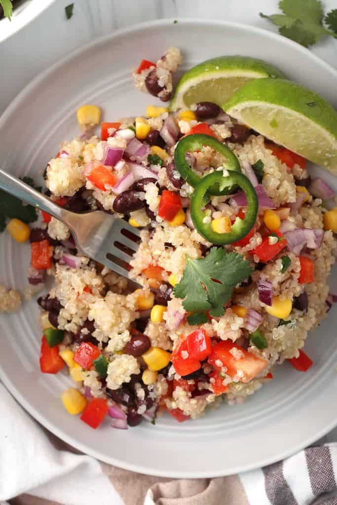 closeup overhead shot of southwestern quinoa salad on a white plate with a silver fork