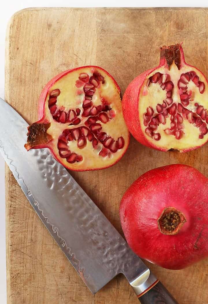 Pomegranate cut in half on a cutting board