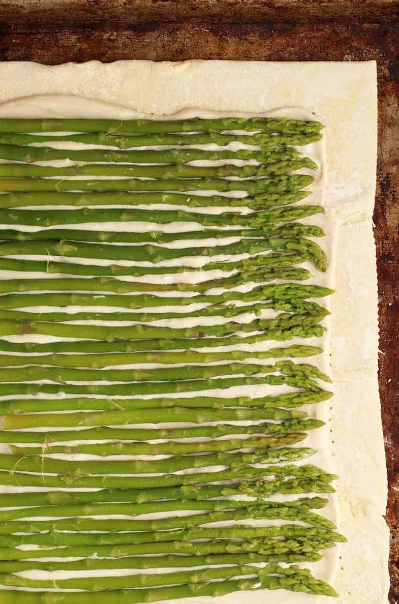 Raw asparagus covering a raw puff pastry