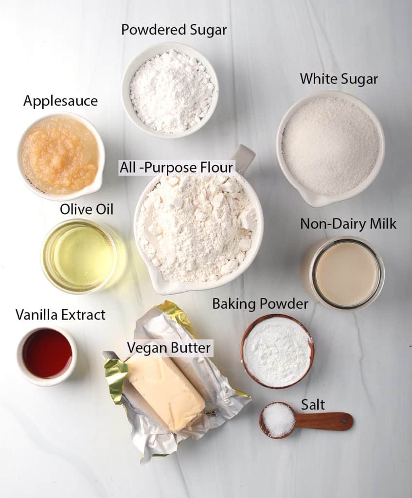All the ingredients needed for vegan vanilla cake measured out on a white marble background