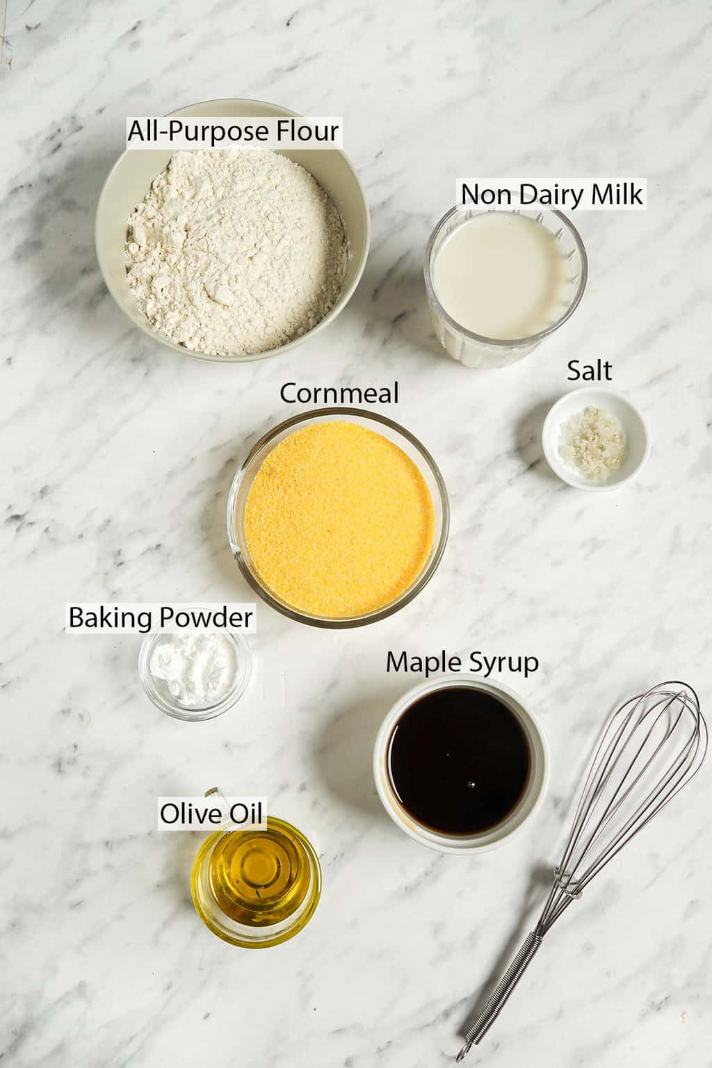 Ingredients for cornbread muffins measured out and placed on a marble countertop.
