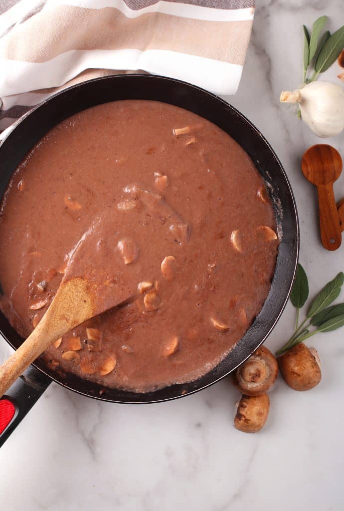 Finished gravy in a skillet with a wooden spoon