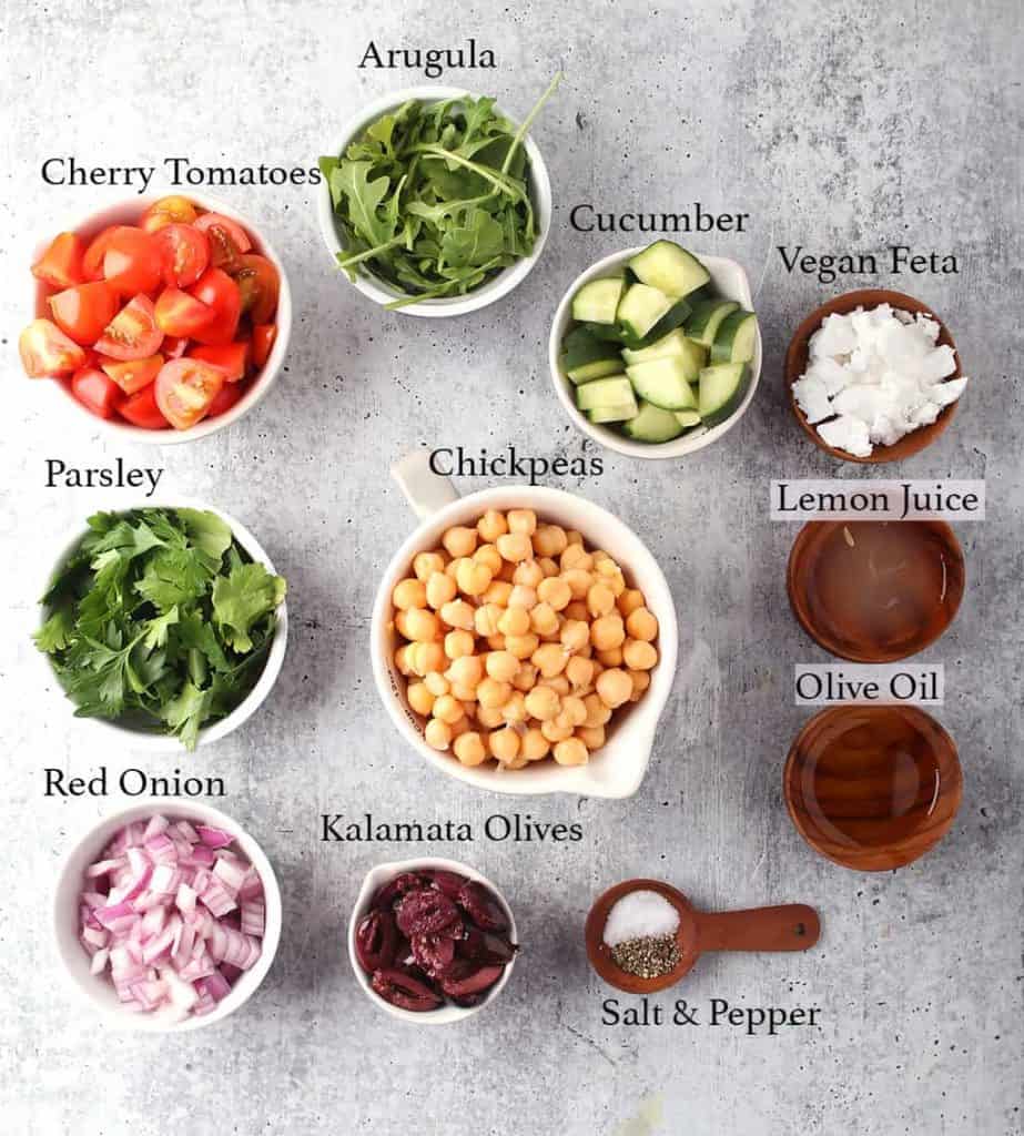 Ingredients for Greek salad measured out and placed on a concrete countertop