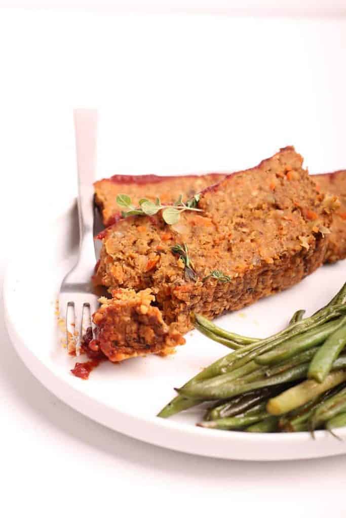 Two slices of vegan meatloaf on a white plate