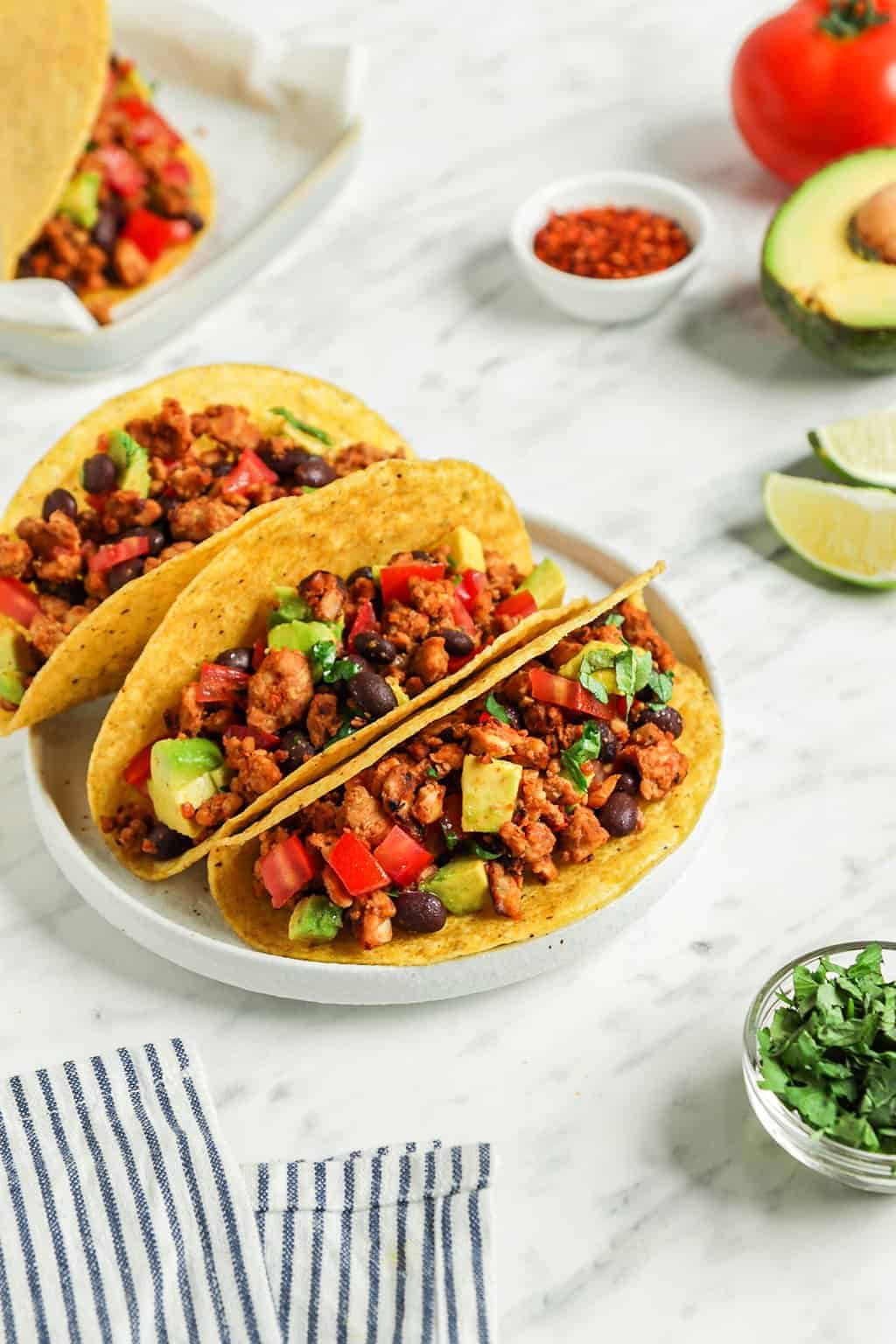 three vegan tacos on white plate with lime slices