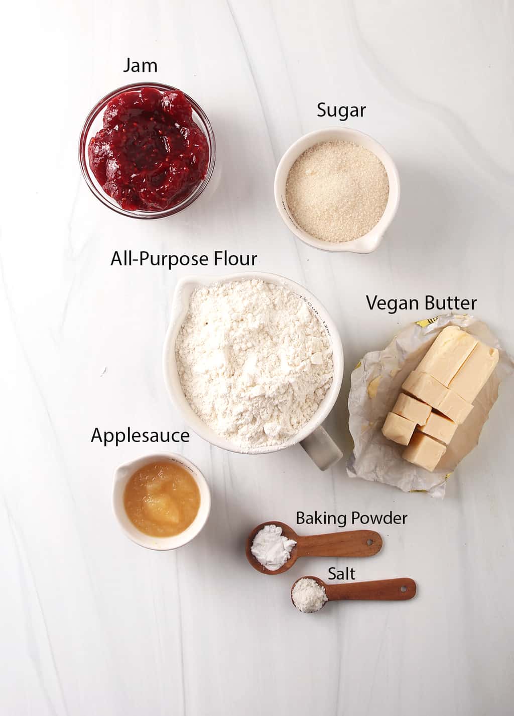 Ingredients for vegan thumbprint cookies measured out and placed on a marble countertop. 