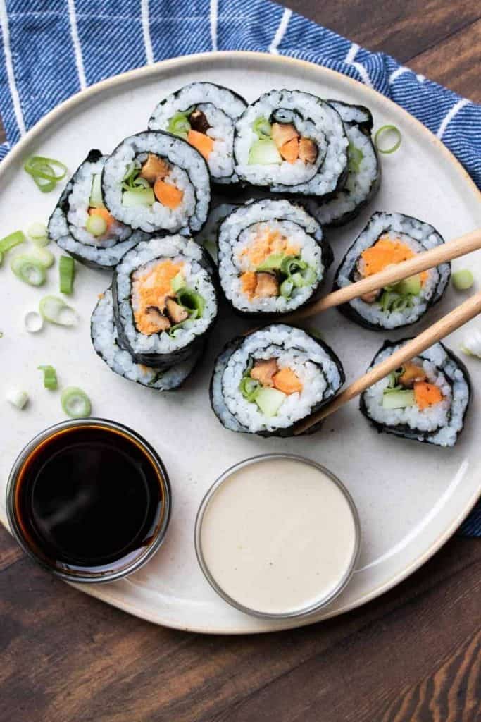 Plate of vegan sushi with dipping sauce and chopsticks