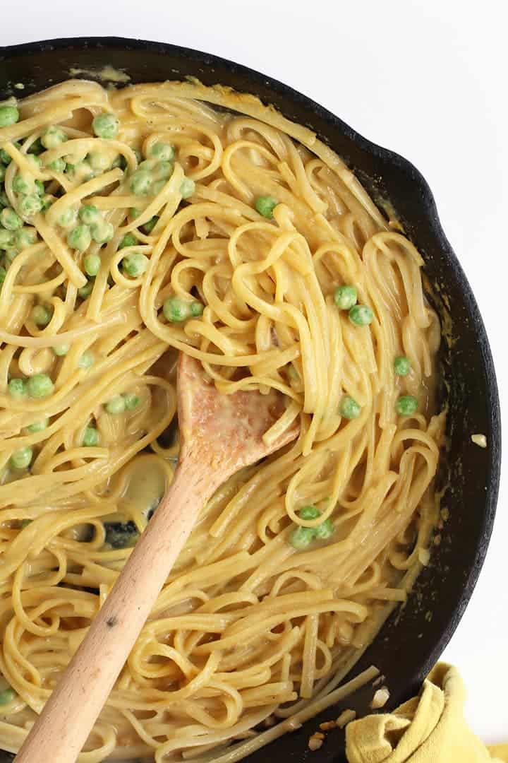 Pasta and peas in a cast iron skillet with a wooden spoon