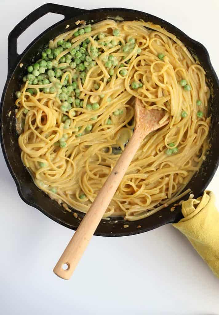 Finished pasta dish in a cast iron skillet with a wooden spoon