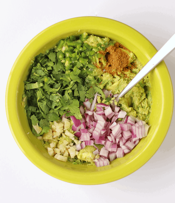 Avocado, onions, and cilantro in a green bowl